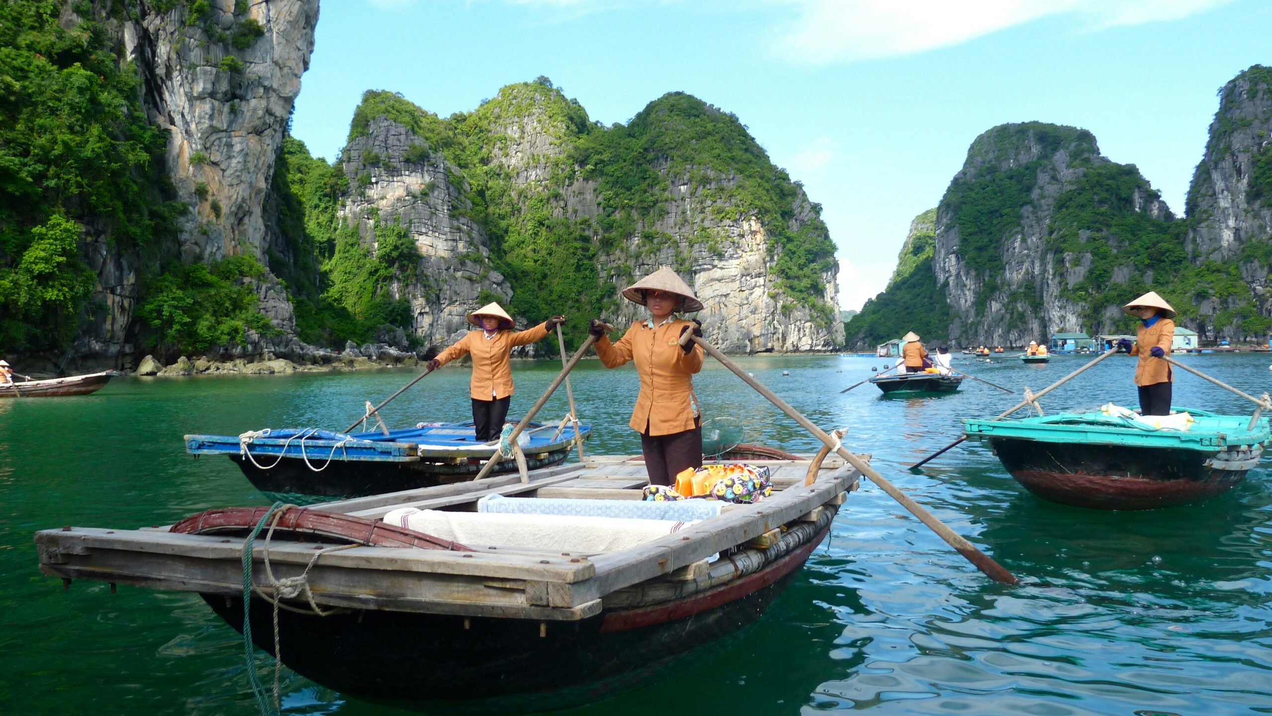 Ha Long Bay travel guide: Vietnamese women rowing traditional boats between limestone karst islands